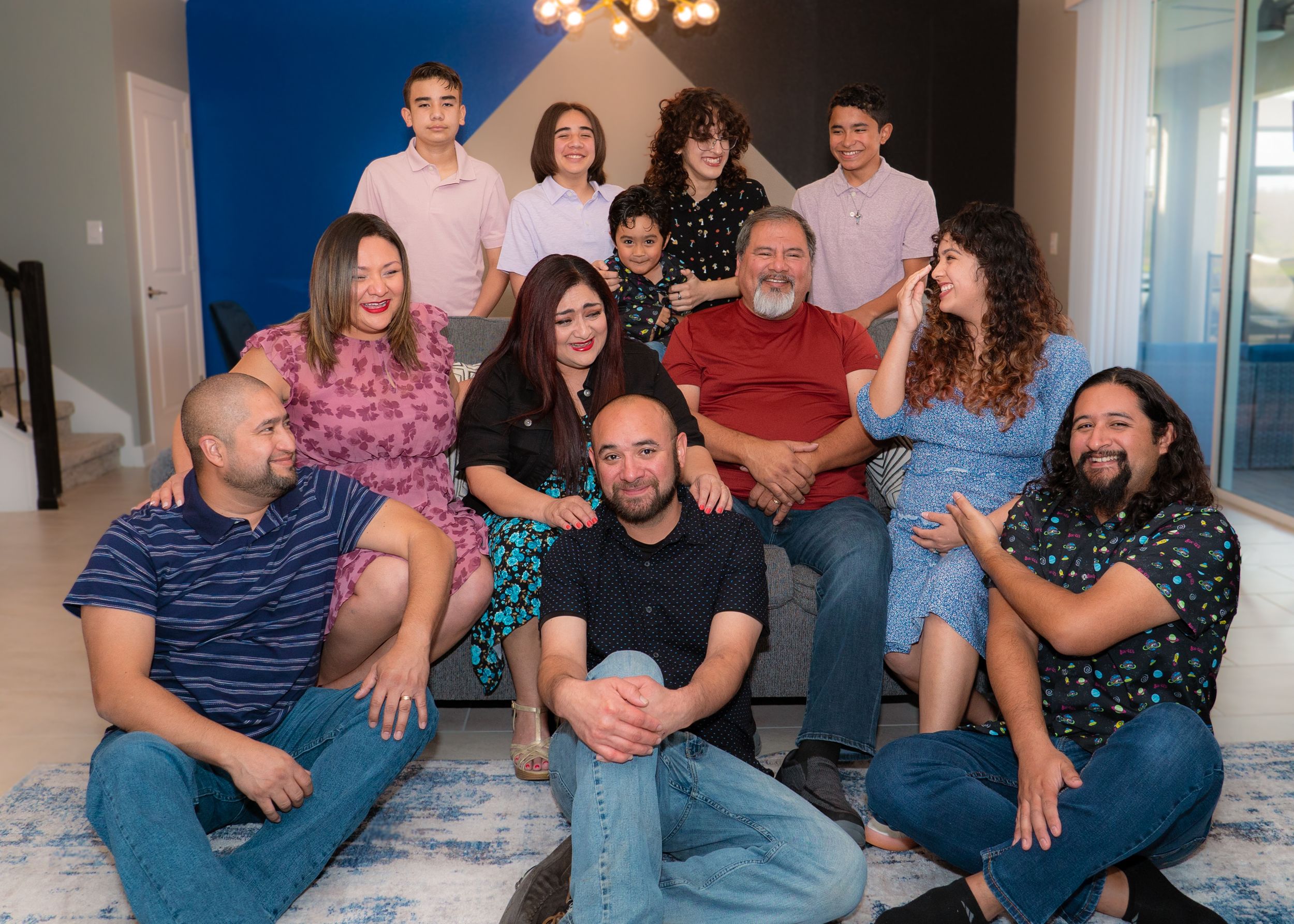 Large multigenerational family laughs together during a candid group portrait at home.