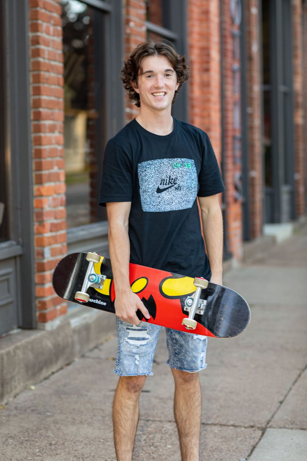 Urban skateboarding photo with colorful Nike board against brick building backdrop.
