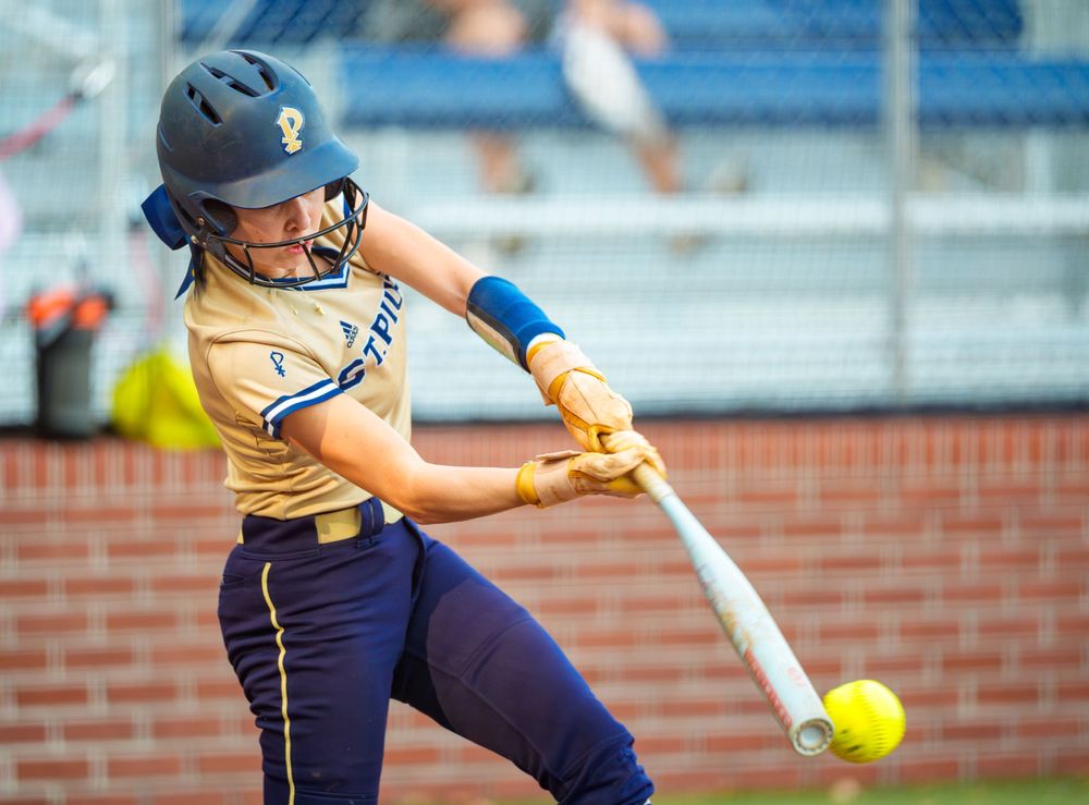 High school female softball athlete, making contact with her bat at the plate.