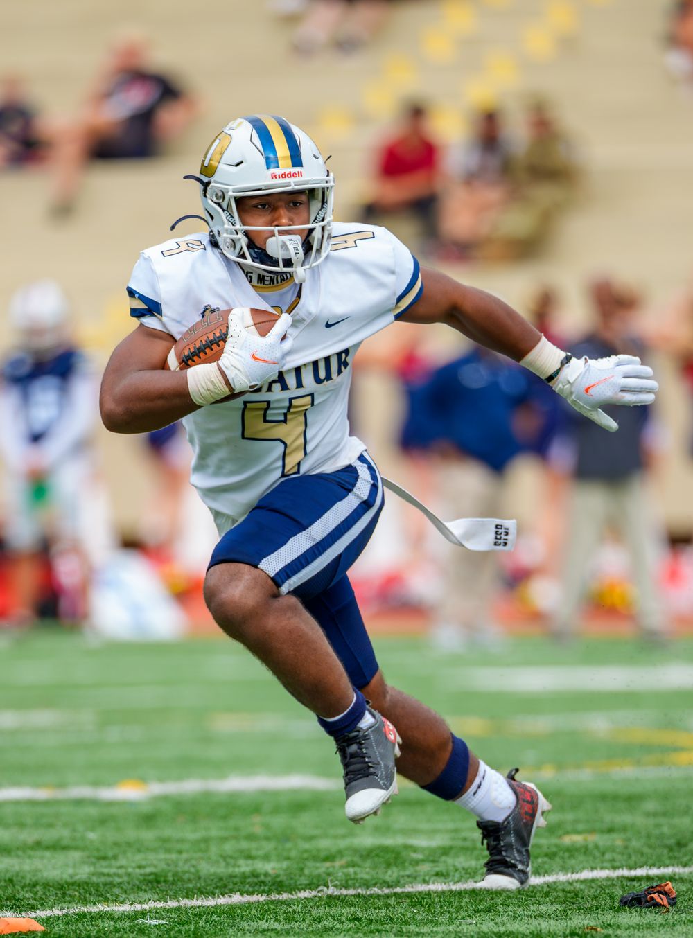 Football player carrying ball makes dynamic cut during game.