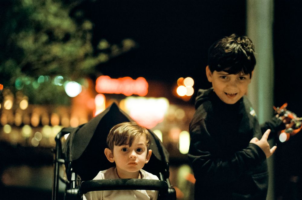 Two young figures enjoying a festive nighttime scene with blurred lights in the background.