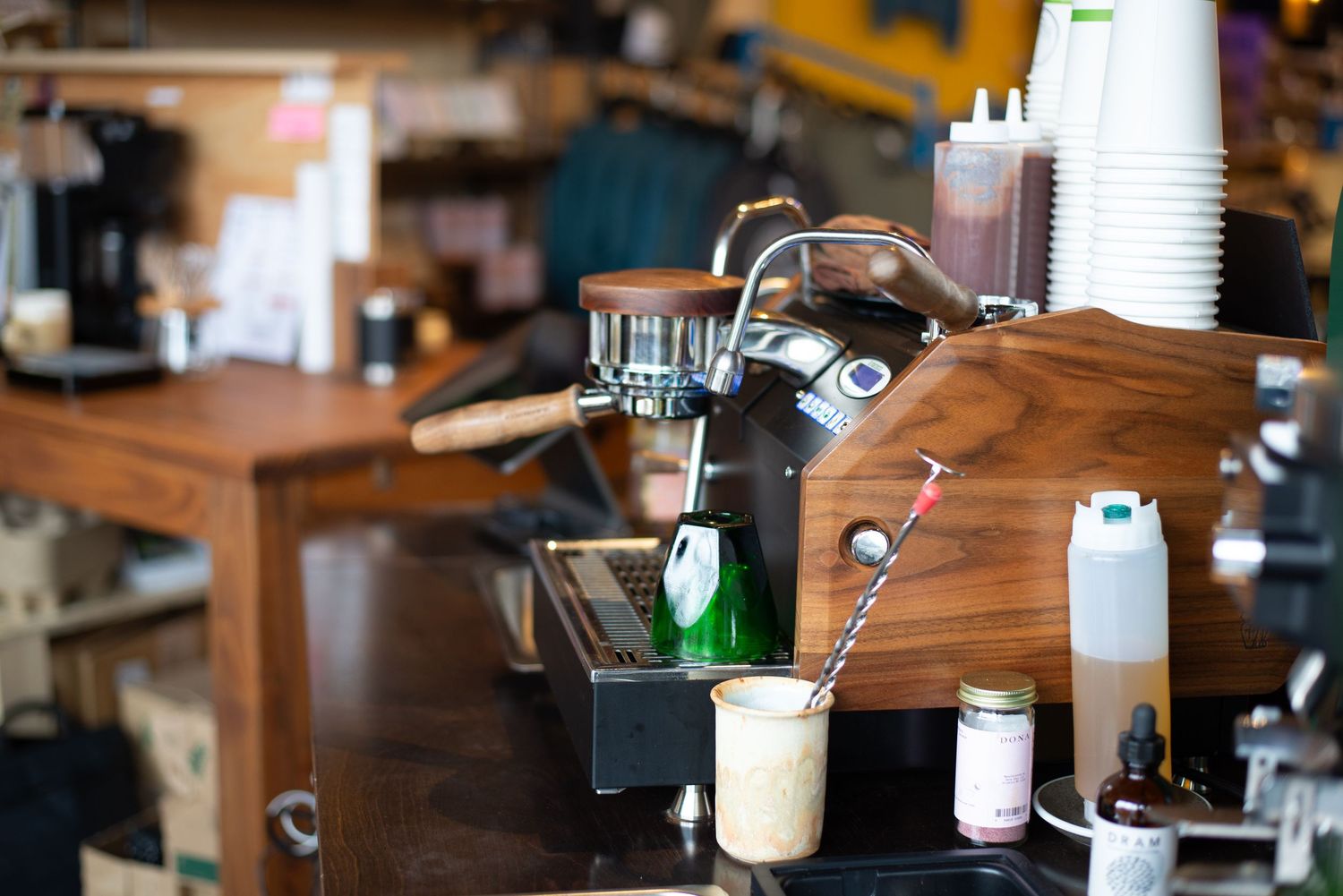 Professional espresso machine on a wooden counter in a cozy coffee shop setting.