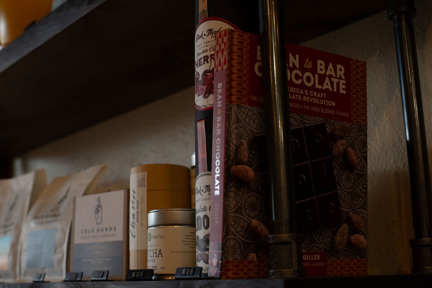 Artisan chocolate bars and coffee products displayed on a rustic wooden shelf in a boutique shop.