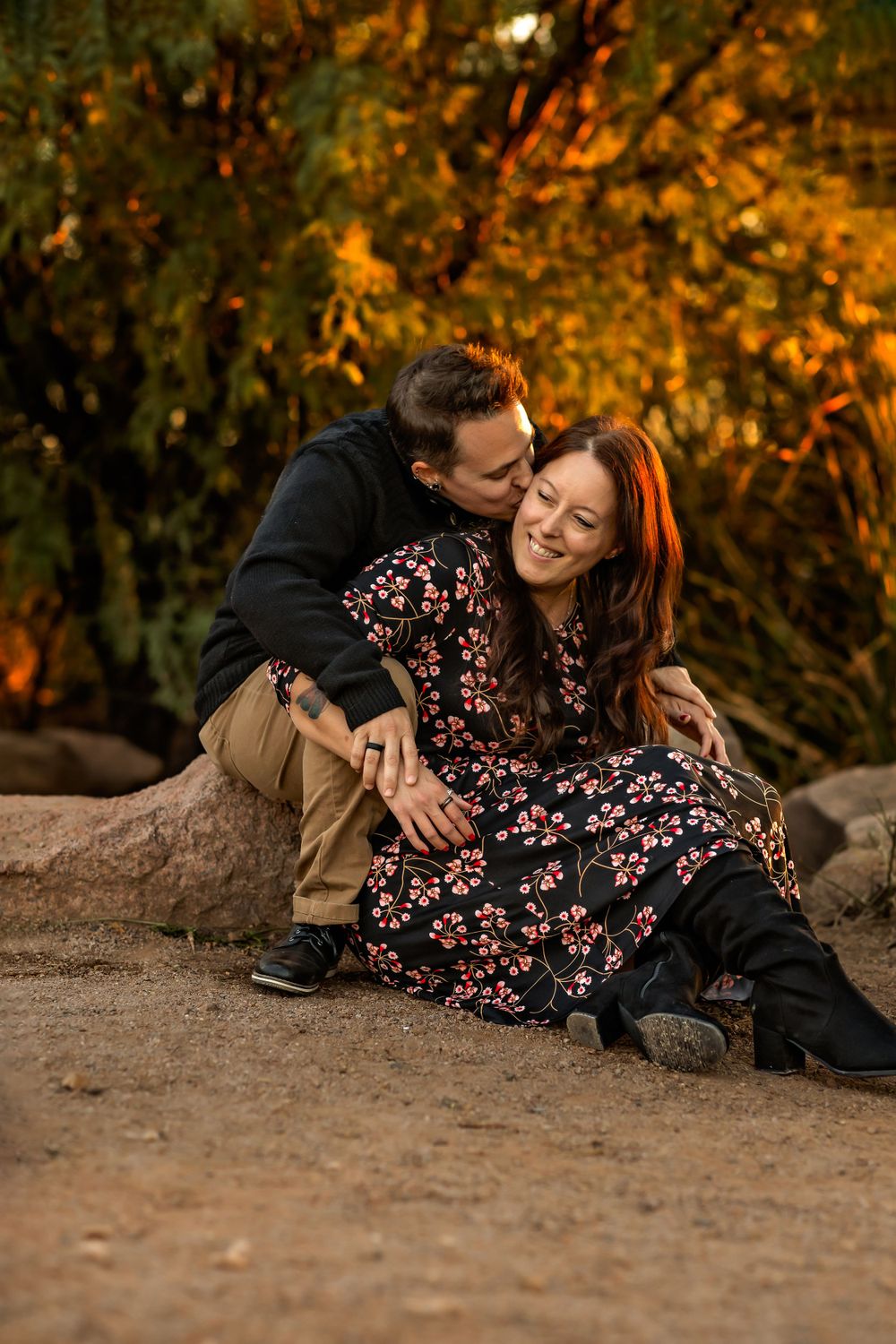 Couple sharing intimate moment on ground against autumn foliage background at golden hour.