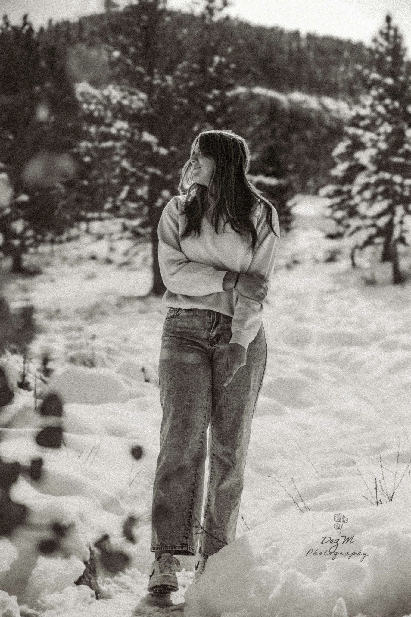 Black and white photo of someone walking through deep snow in winter landscape.