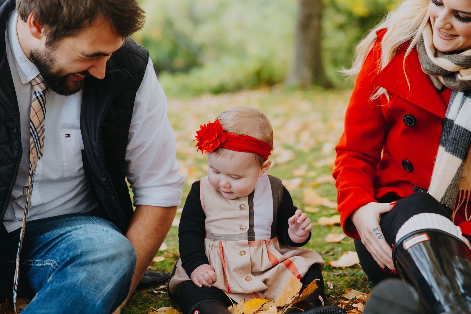 Family enjoying an autumn day outdoors in a park with colorful fallen leaves.