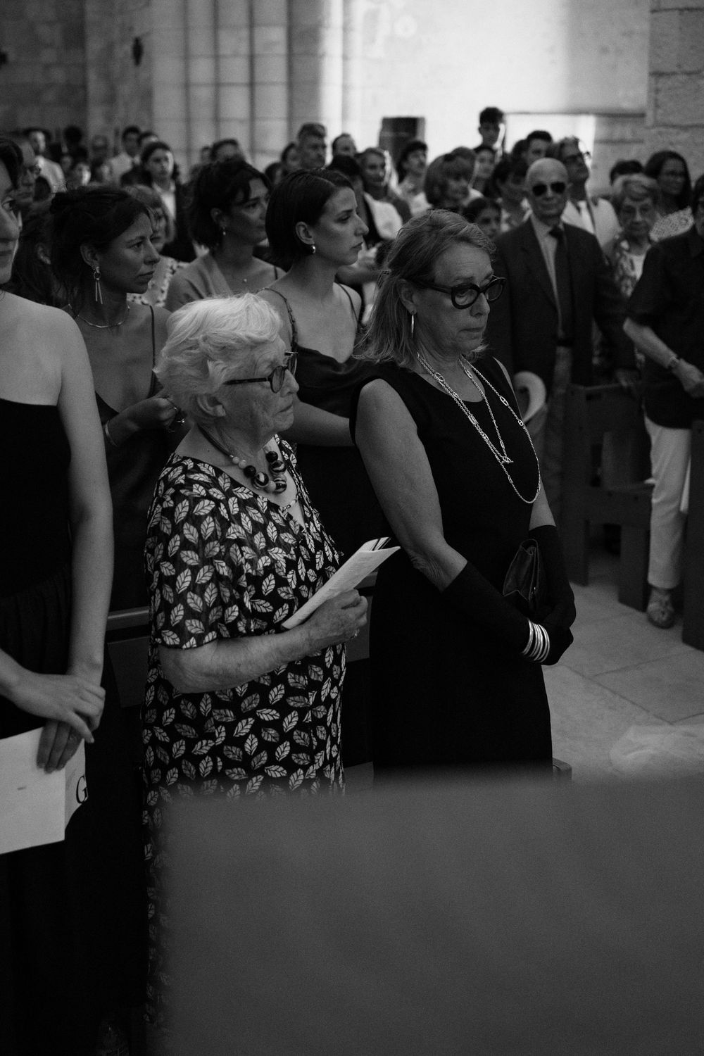 A crowd of people gathered at an event, with some spectators watching intently in black and white.
