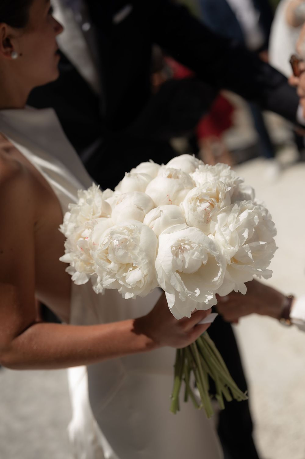 A close-up view of elegant white peonies in a bridal bouquet against a light background.