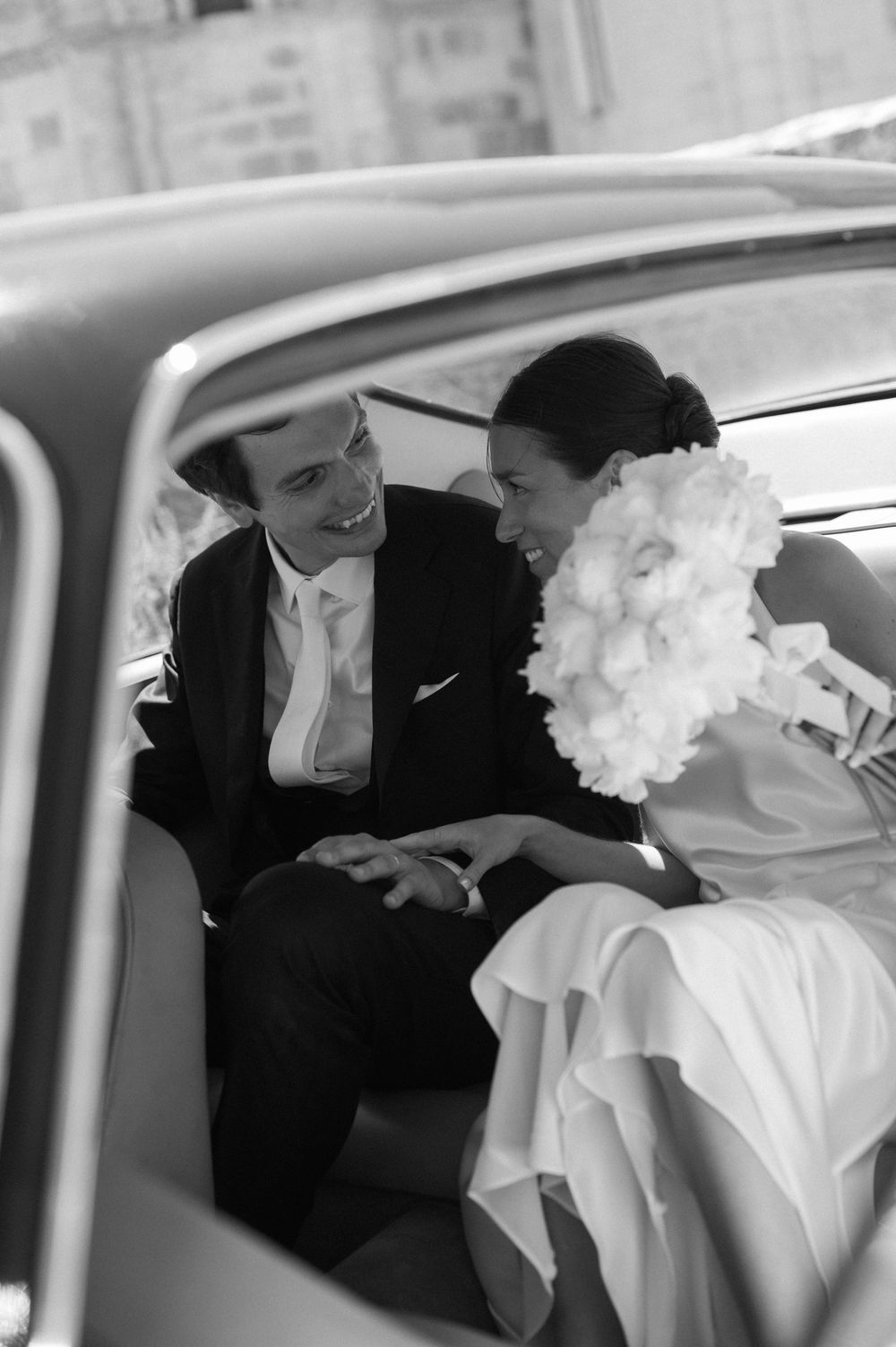 Black and white photo series showing a romantic moment between a couple in formal attire inside a vintage car.
