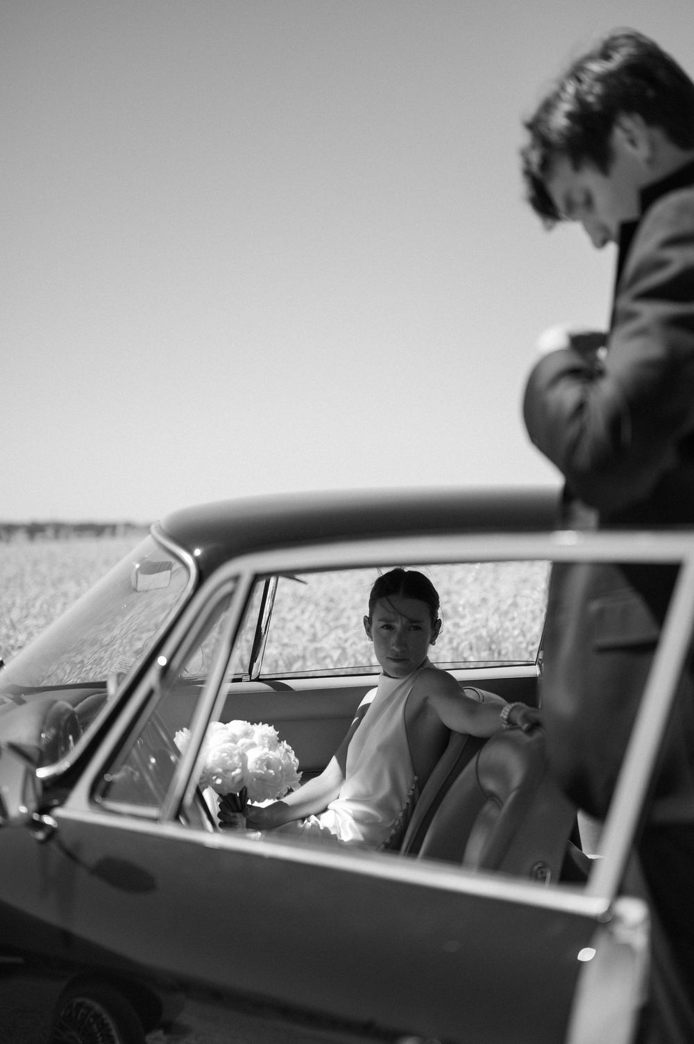 Black and white photo of people inside a vintage car looking through windows.