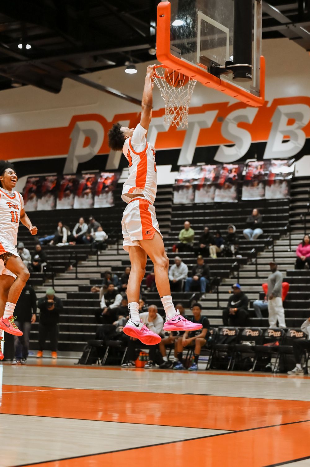 Multiple action shots show basketball players jumping and dunking on an orange court with stadium seating.