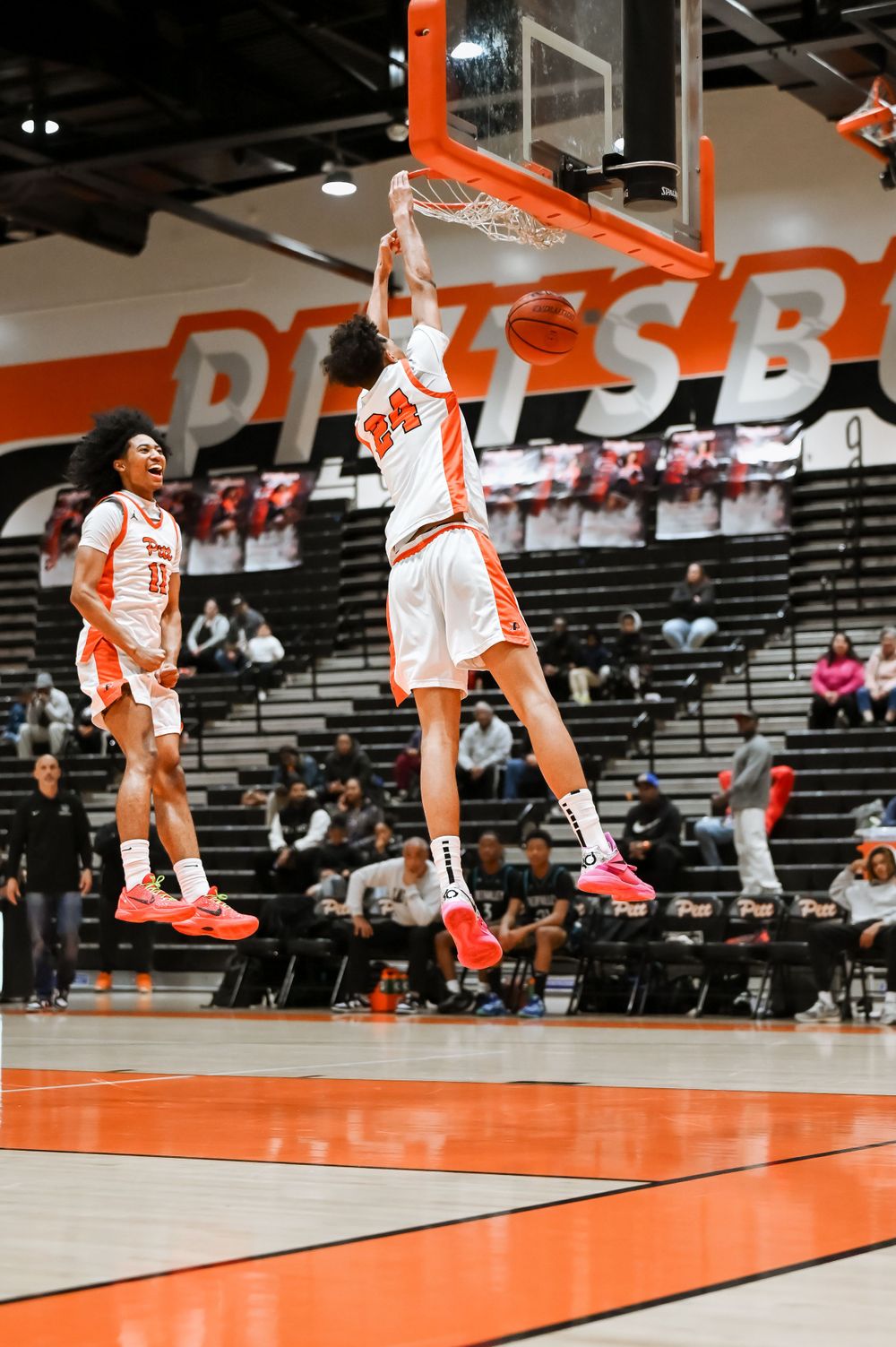 Basketball players execute impressive jumps and dunks during a game sequence on their home court.