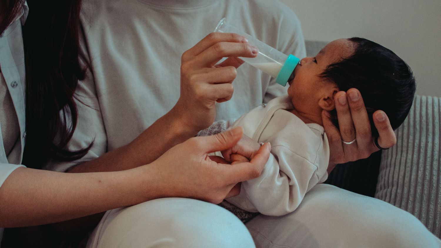 newborn baby being bottle fed by both parents