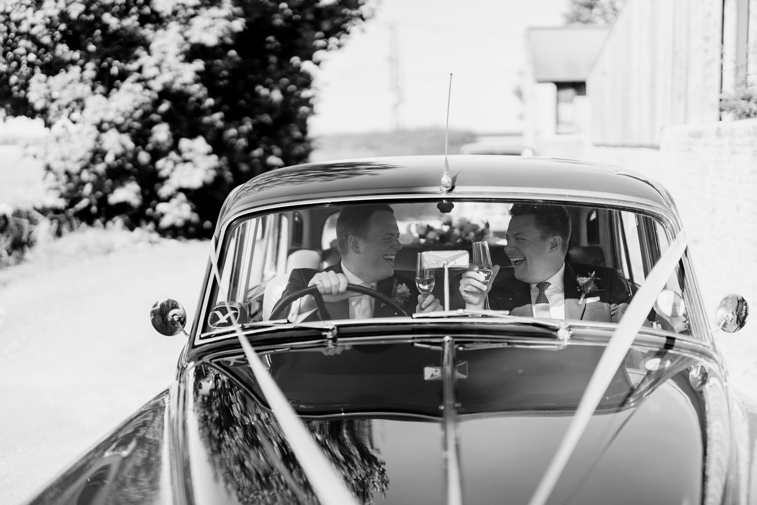 A classic vintage car adorned with wedding decorations photographed in black and white.