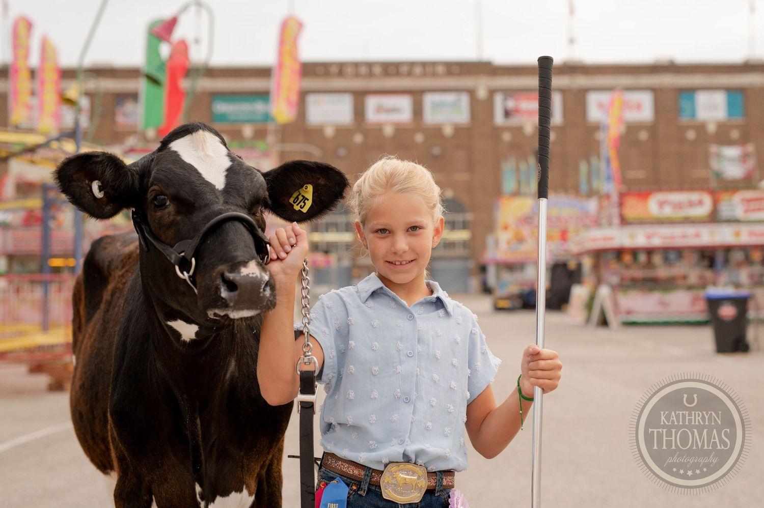 Young exhibitor poses with black and white dairy cow at county fair.