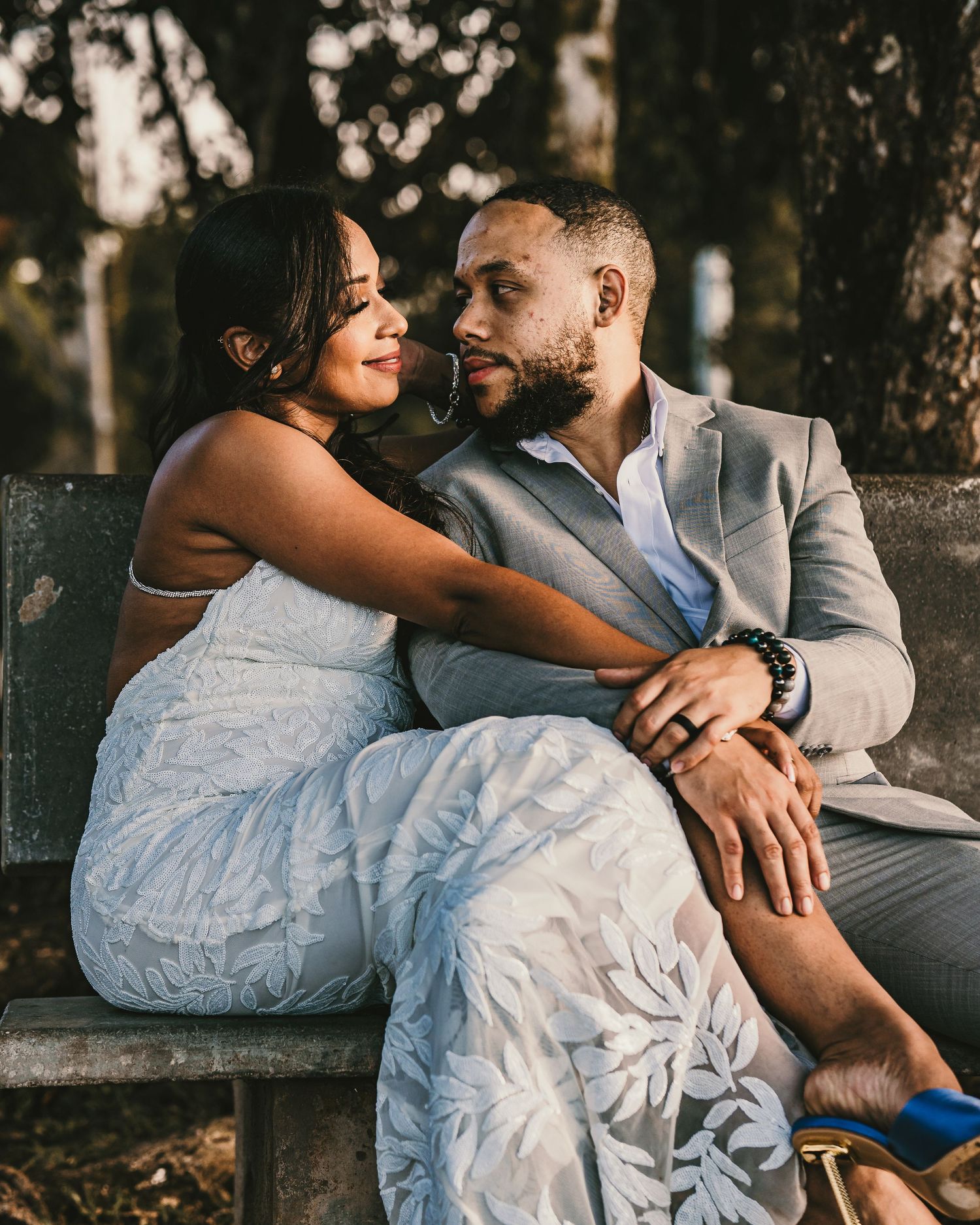 Romantic outdoor wedding photo of a couple relaxing on a bench at sunset.