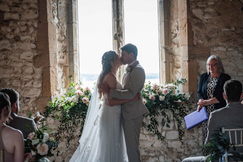 A romantic wedding ceremony takes place in a rustic brick venue with natural light and floral decorations.