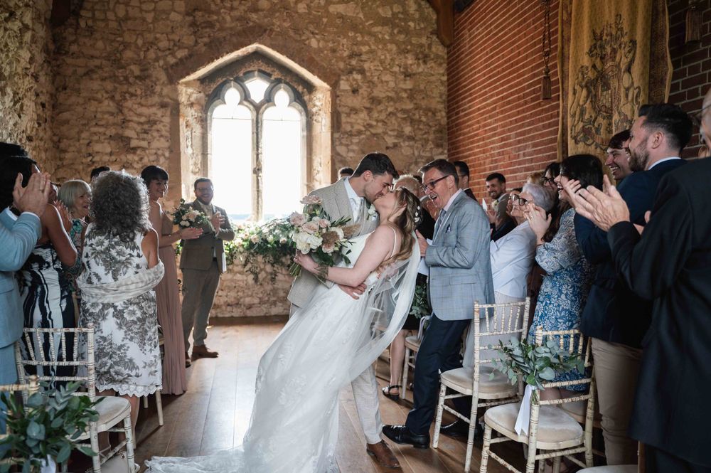 Interior of a rustic stone chapel with arched windows and guests gathered for a celebration.