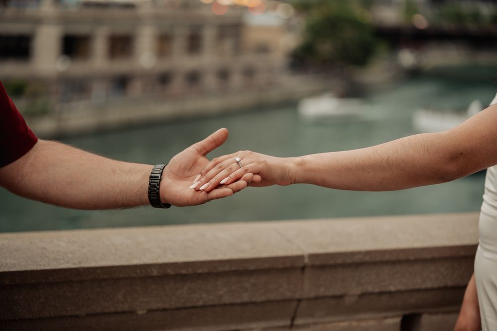 Two hands reaching out towards each other across a stone railing in a tender moment of connection.