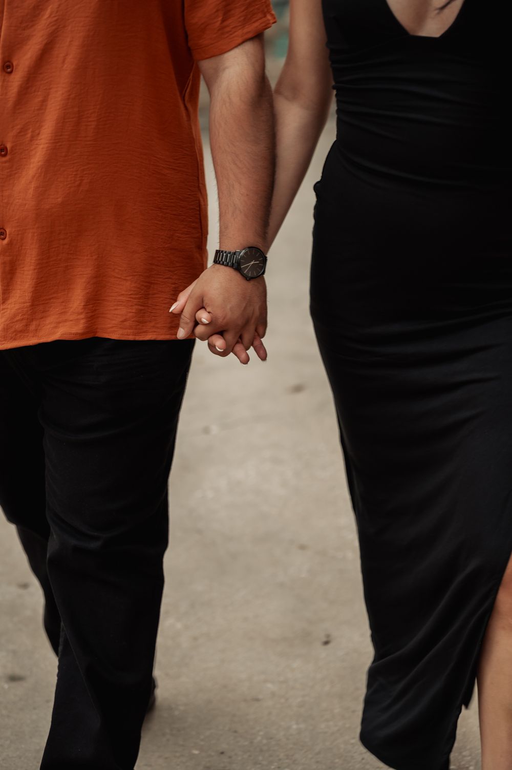 Close-up view of two people holding hands while wearing contrasting outfits.