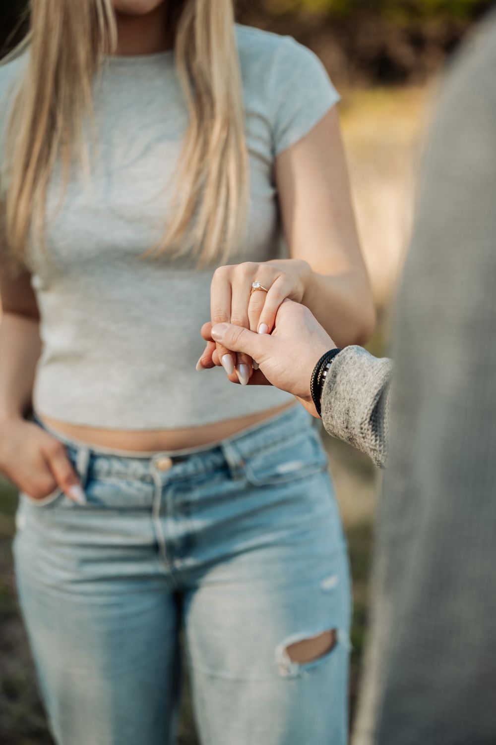 Close-up fashion detail of light blue jeans and cropped grey top showing casual style and fit.