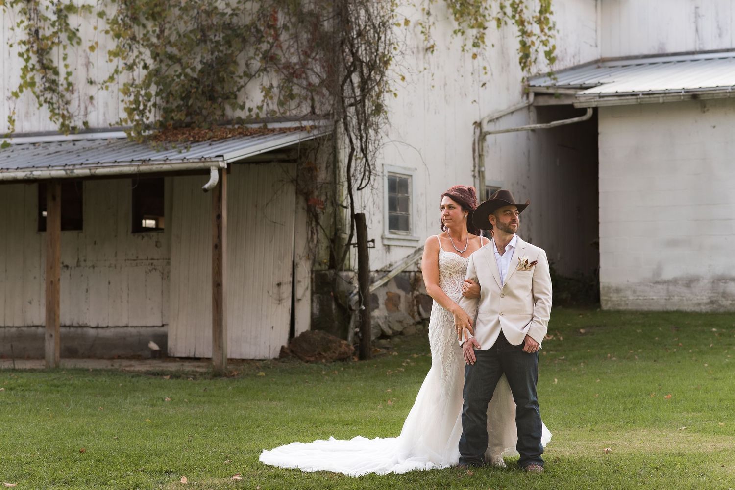 Romantic couple posing against white building exterior with climbing vines.