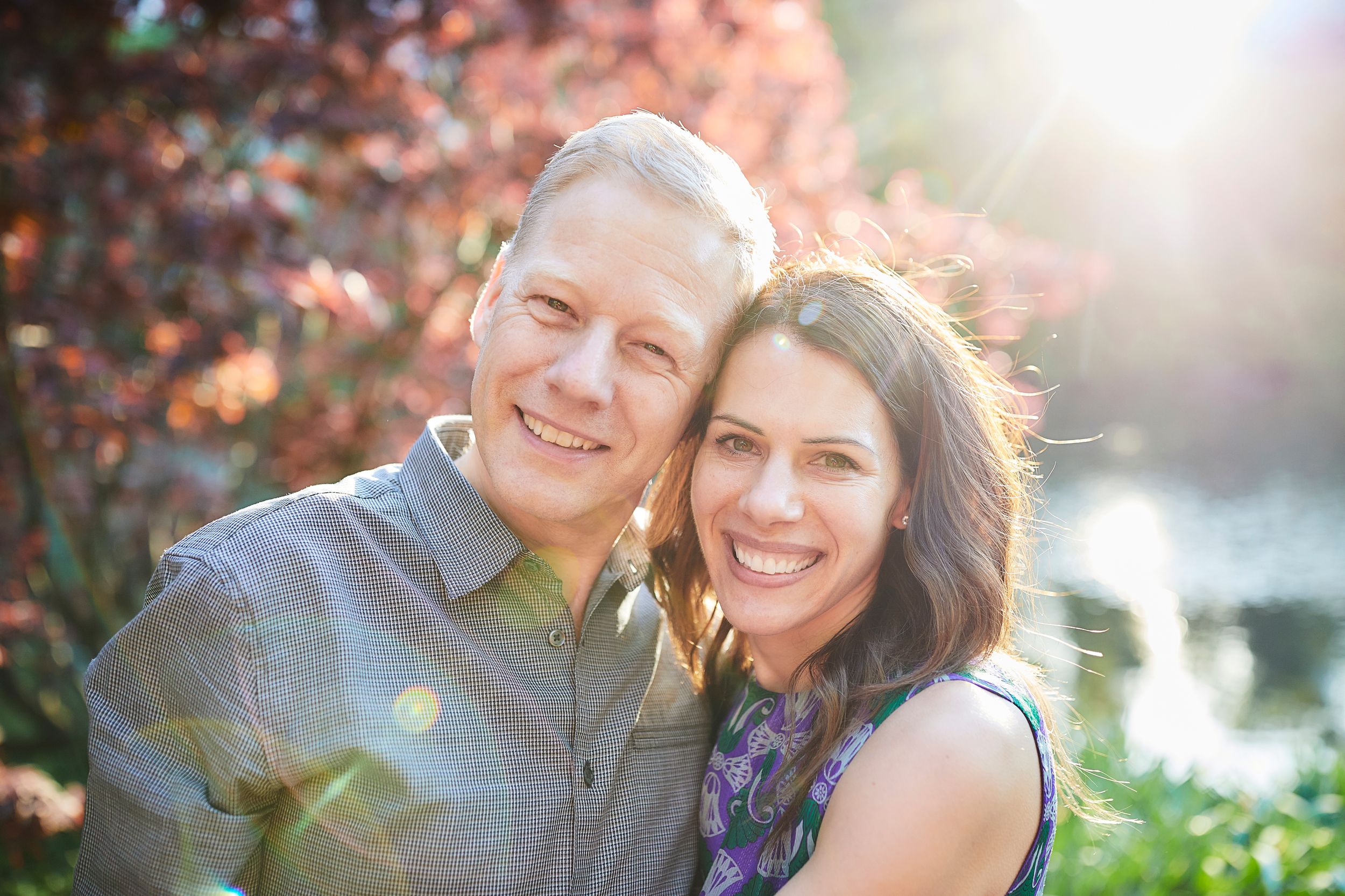 A joyful outdoor portrait with sunlit trees and warm lighting in the background.