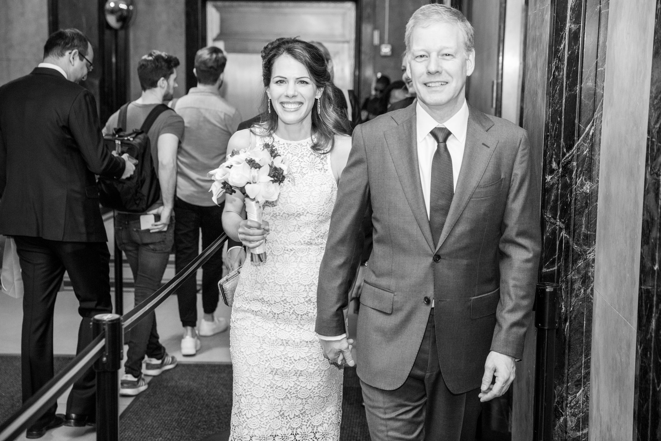 A black and white wedding photo showing a couple walking down steps in formal attire.
