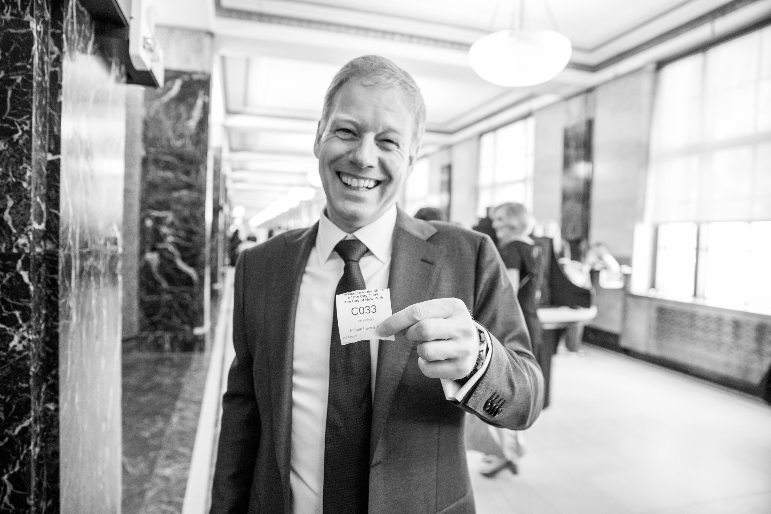 Black and white portrait in an elegant marble hallway showing joyful expression.