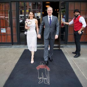 At The Bowery Hotel newlyweds exit onto a black carpet while a doorman holds the door.
