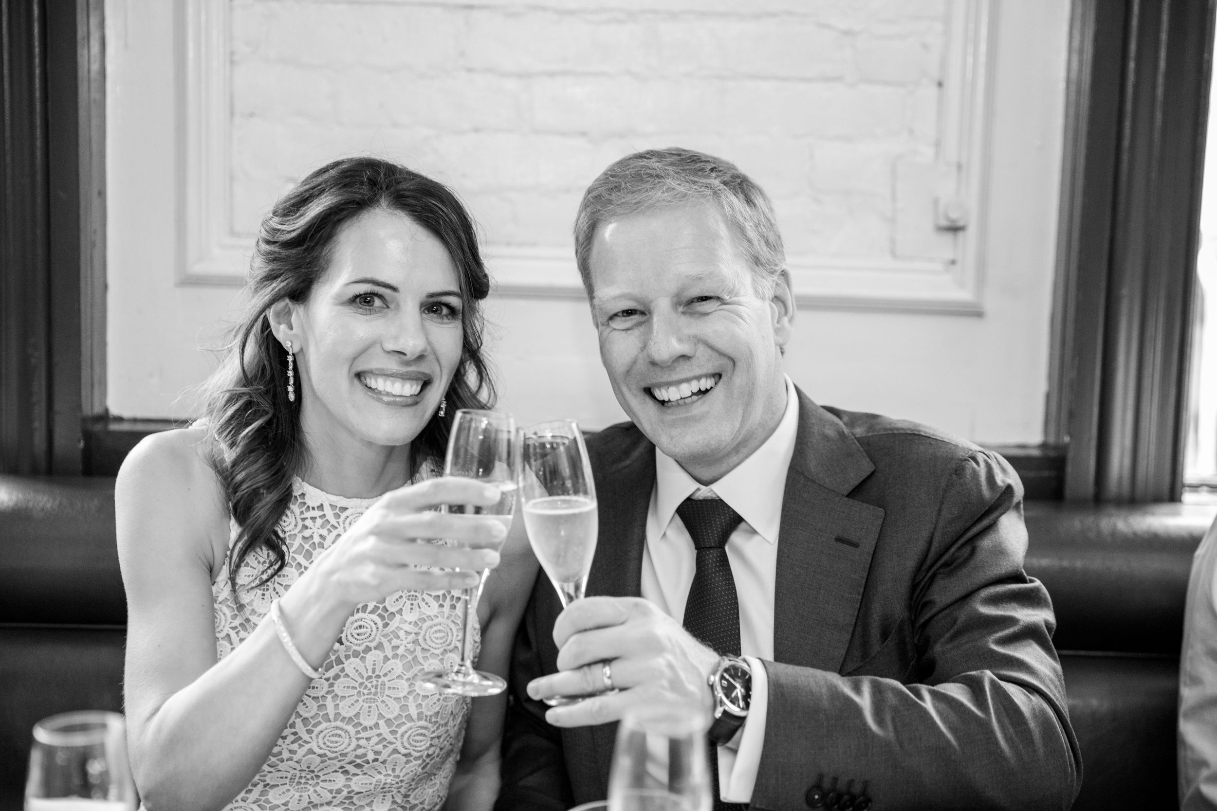 A black and white photo of newlyweds toasting with champagne glasses.