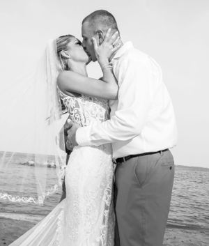 Romantic black and white beach wedding photo with ocean in background.