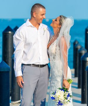 Seaside wedding portrait with bright blue ocean and dock in background.