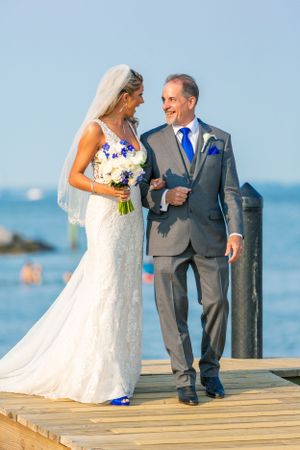 A waterfront wedding scene on a wooden dock by the ocean.