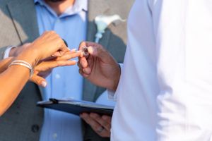 Close-up of hands exchanging wedding rings during ceremony.