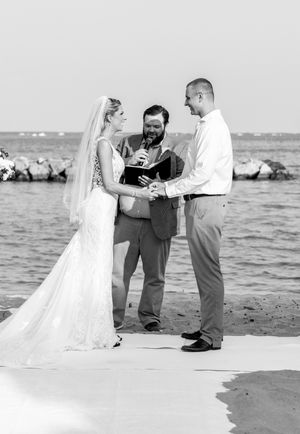 A black and white beach ceremony photograph with waves in the background.