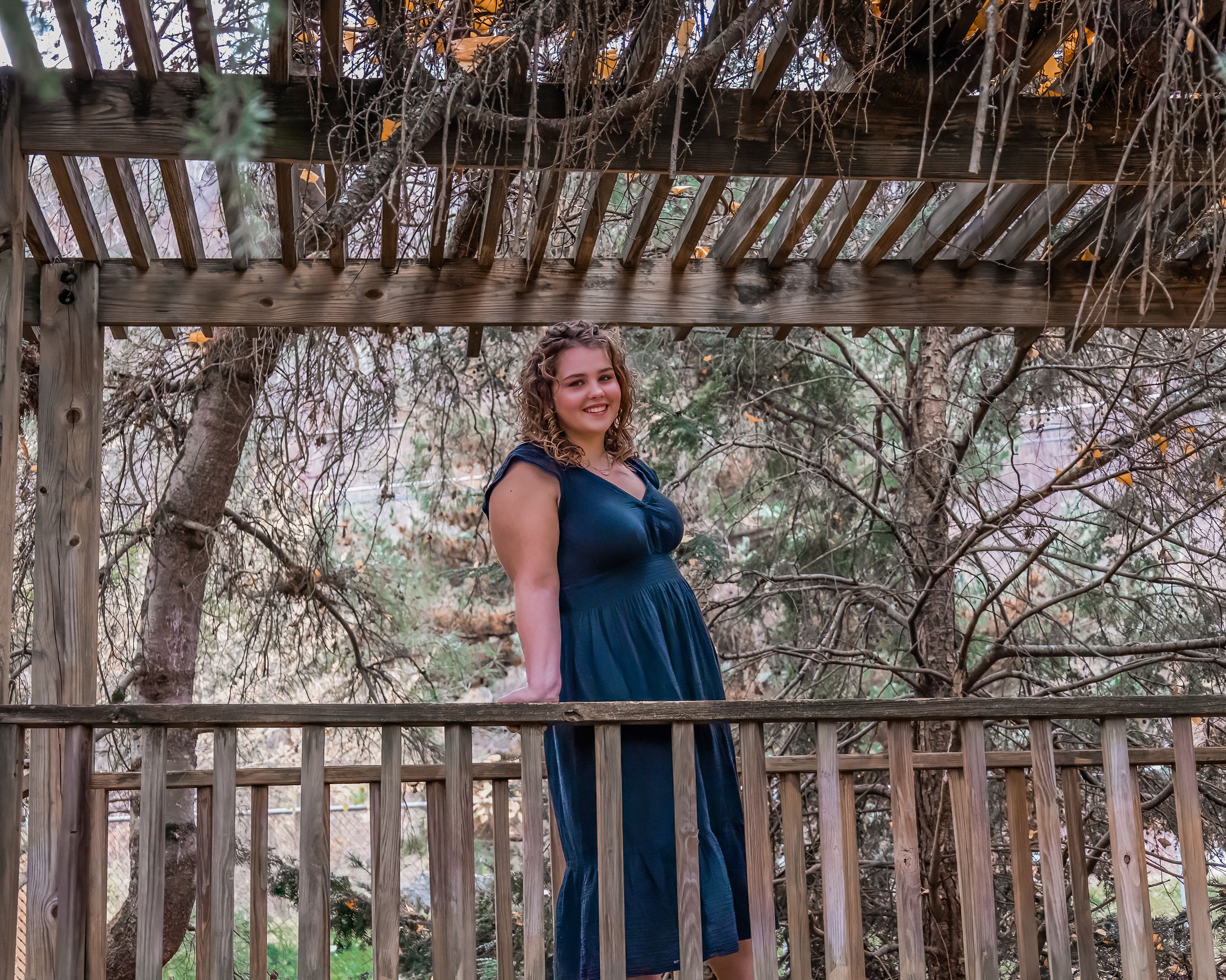 Full length portrait on wooden deck with natural scenery and navy blue dress.
senior photography