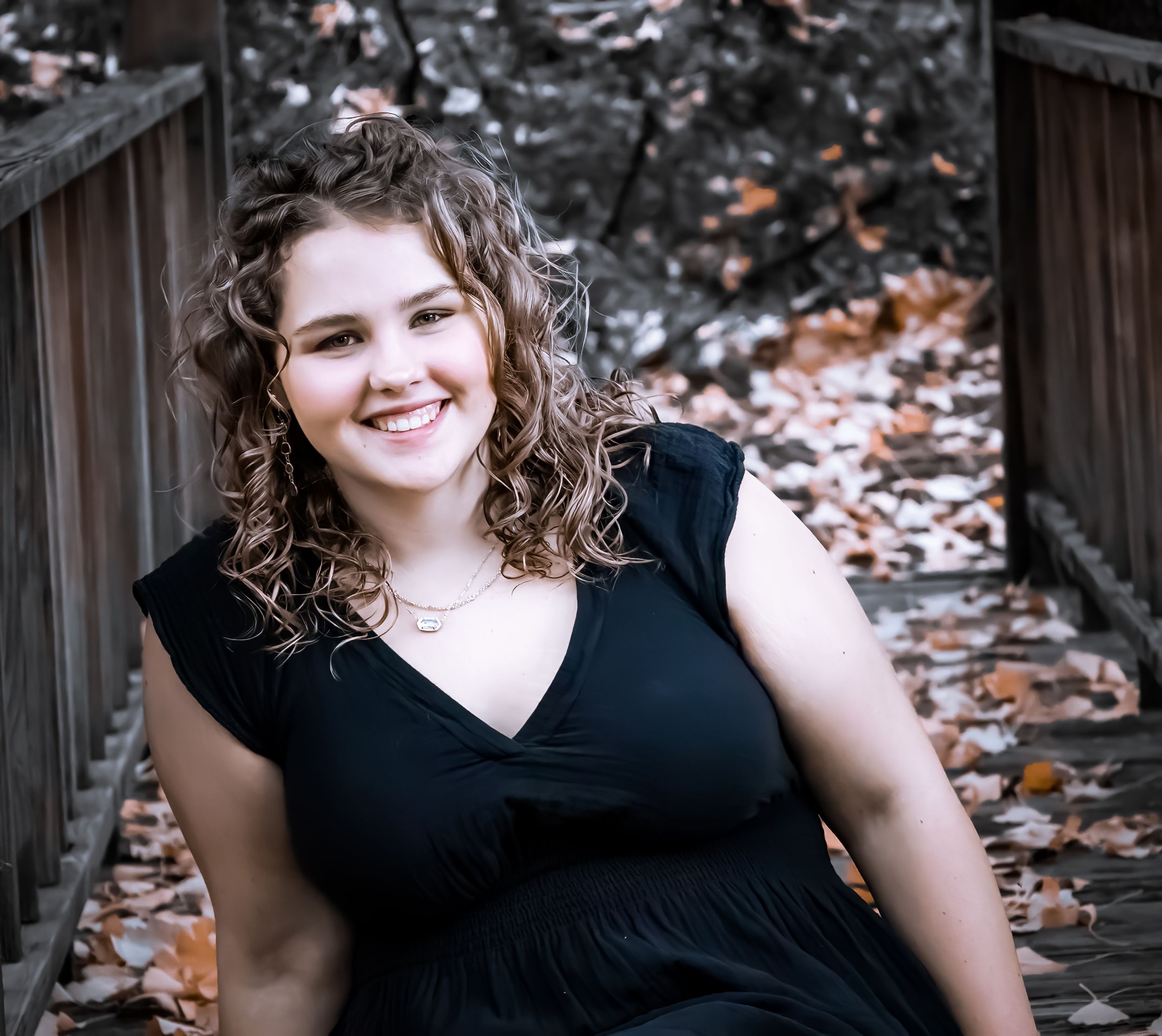 Outdoor portrait on wooden deck with autumn leaves.
senior photography