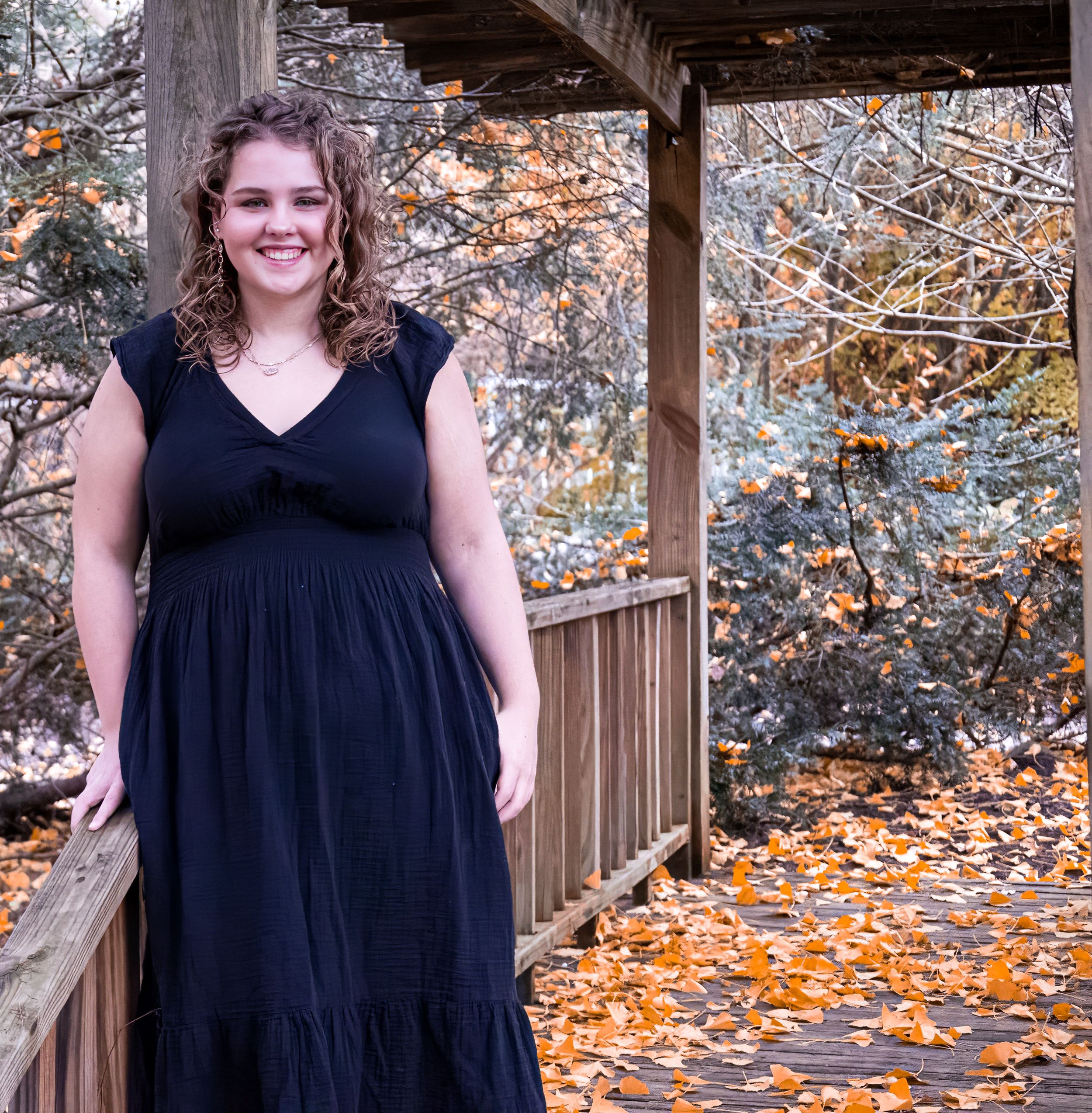 A navy dress seen against fall foliage and wooden structure backdrop.
senior photography