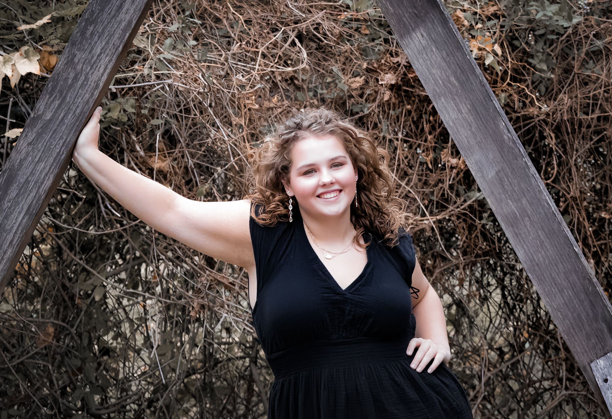 Casual portrait against wooden beams with natural background.
senior photography