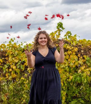 Navy dress against vineyard with red maple leaves falling in the air.
senior photography