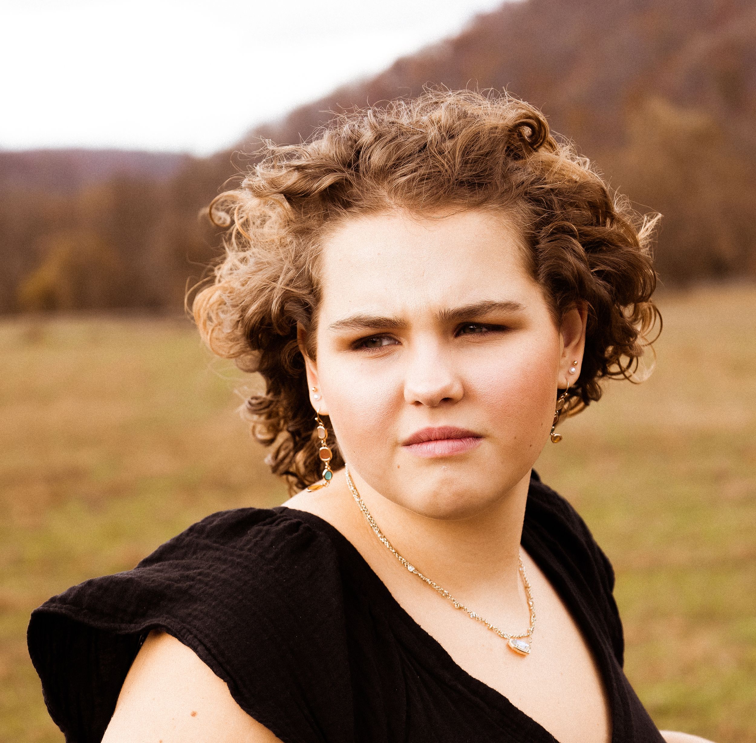 Portrait against autumn landscape with curly hair and black top.
senior photography