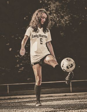 Soccer player in white jersey practices ball control skills on field.
senior photography
soccer senior
