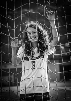 Soccer player in white uniform poses behind goal net in black and white photo.
senior photography
soccer senior