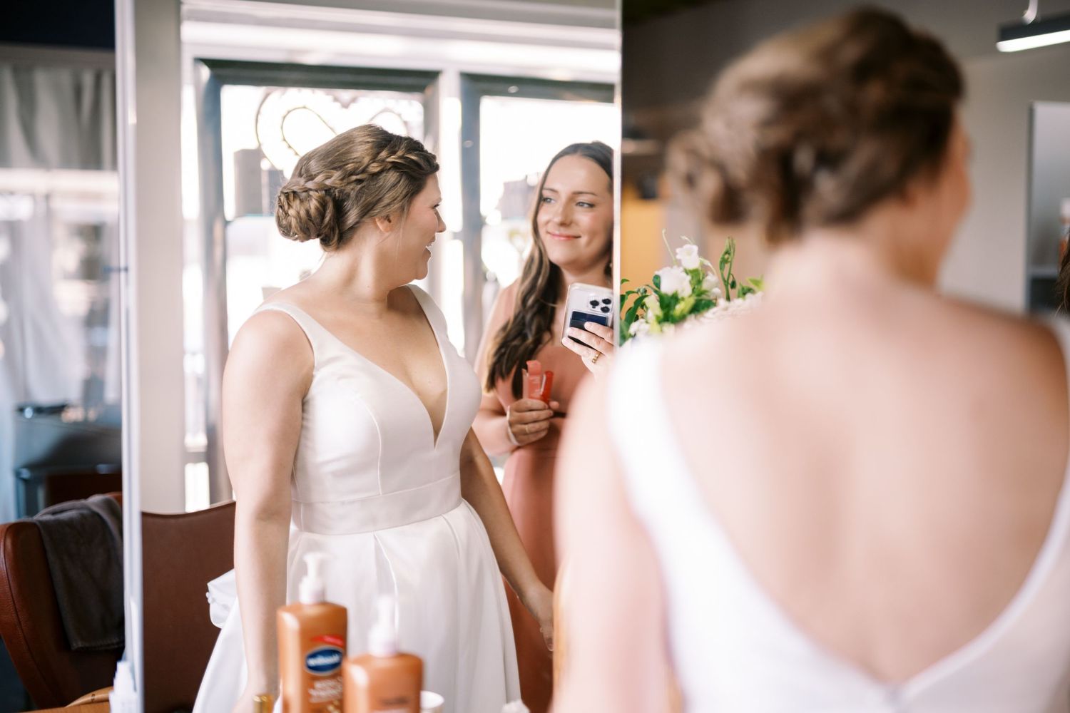 Two people sharing a lighthearted moment together while wearing elegant attire in a bright indoor setting.