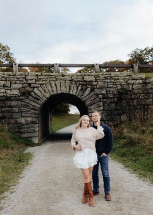 Couple along stone archway path during engagement photo session.