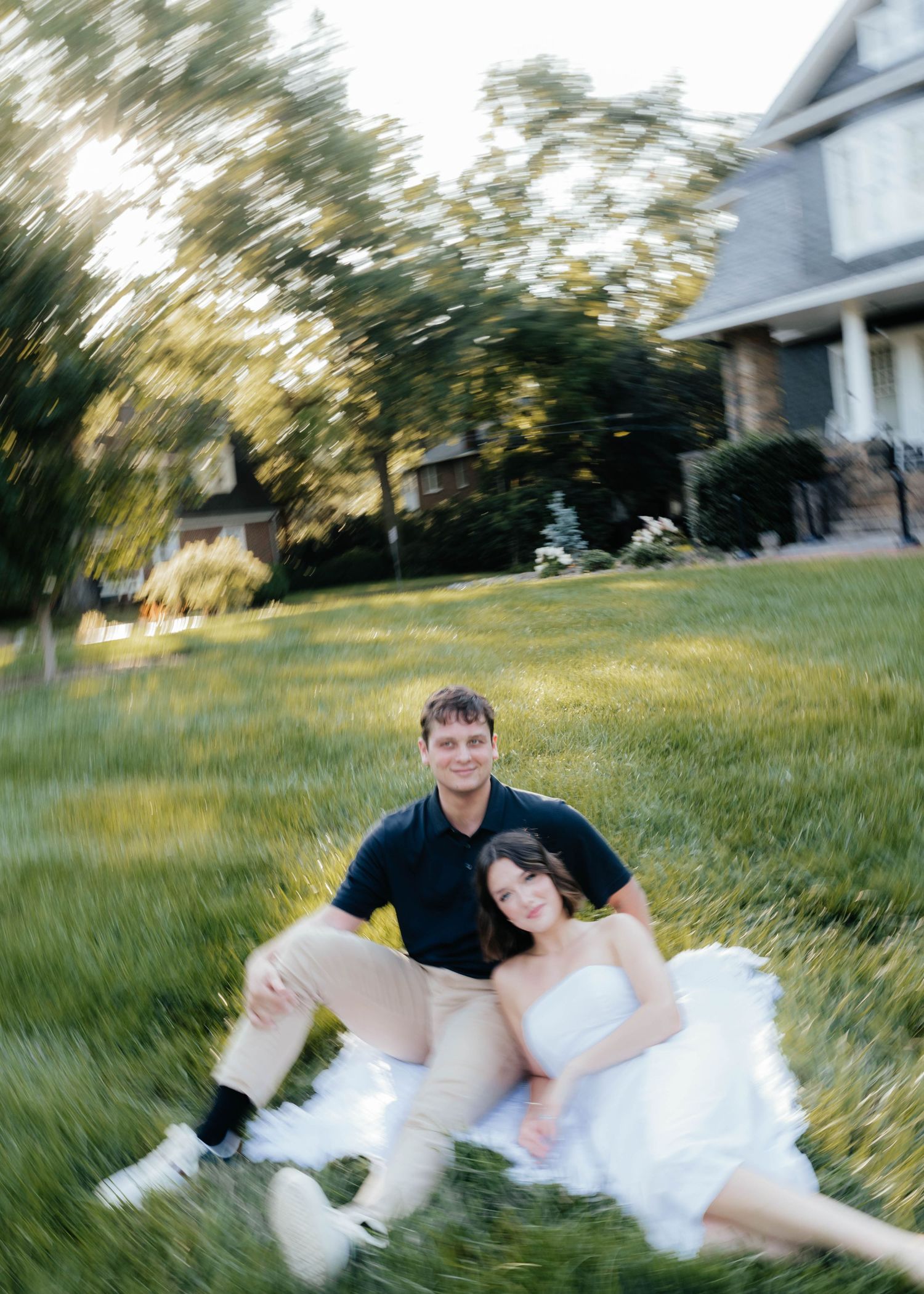 Couple shares intimate moment while lying in sunlit grassy field.