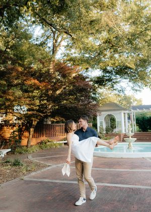 Dancing couple performs elegant moves on brick pavers near a garden gazebo.