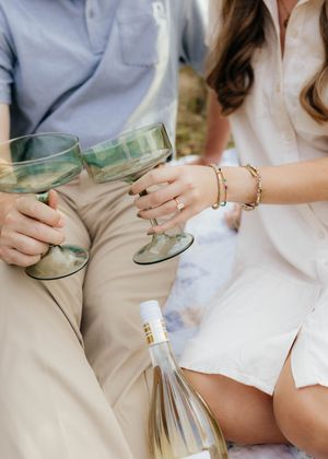 Close-up of vintage glass bottles and picnic setup on white blanket.