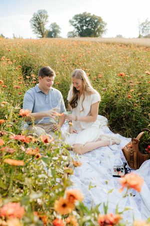 Picnic scene with couple enjoying refreshments among orange wildflowers.